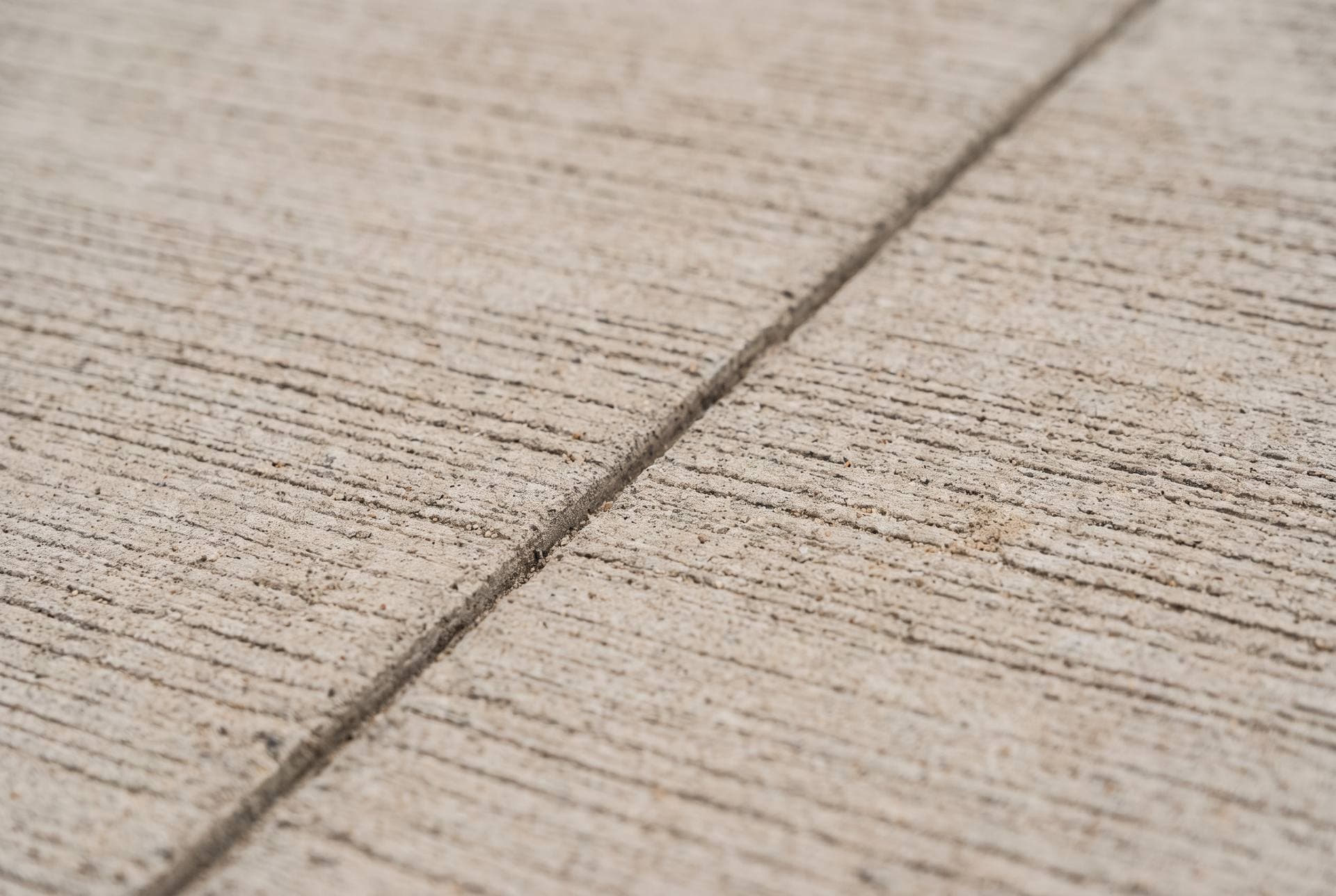 Close-up of broom-finished concrete texture with a control joint