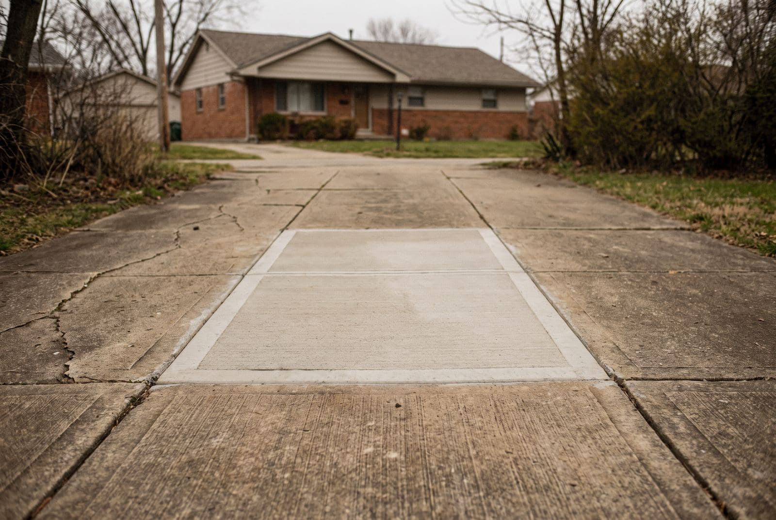 Concrete driveway with one newly repoured section lighter than the surrounding slabs