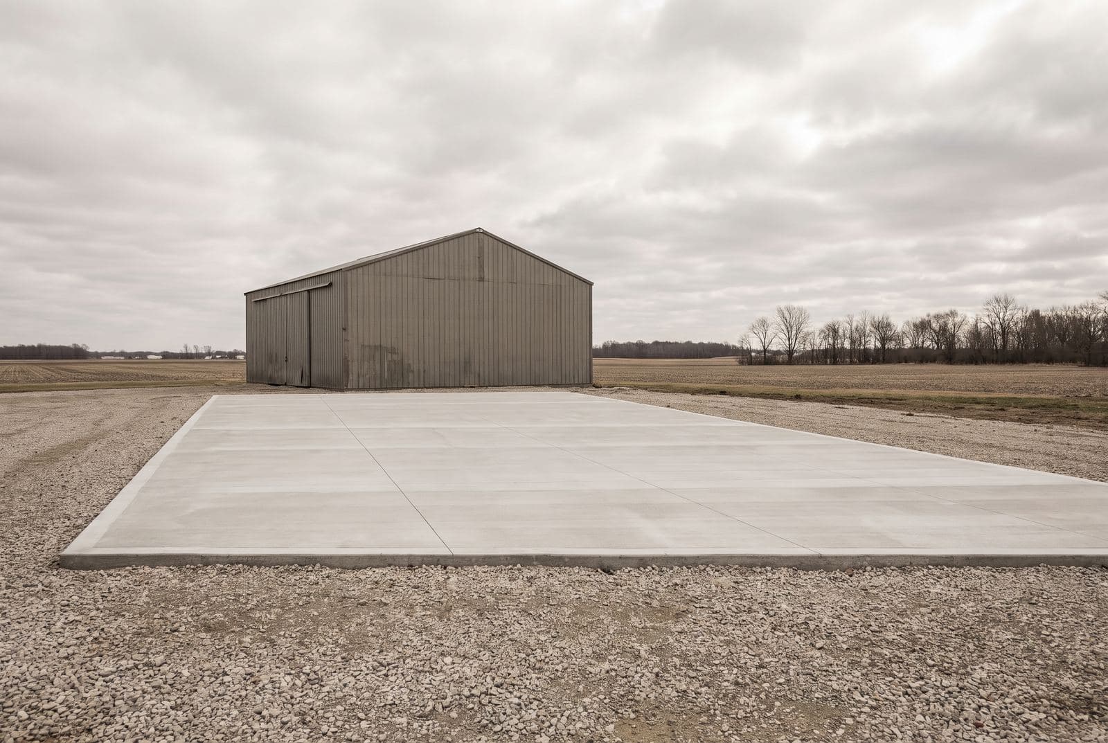 Concrete slab on a gravel base beside a metal pole barn