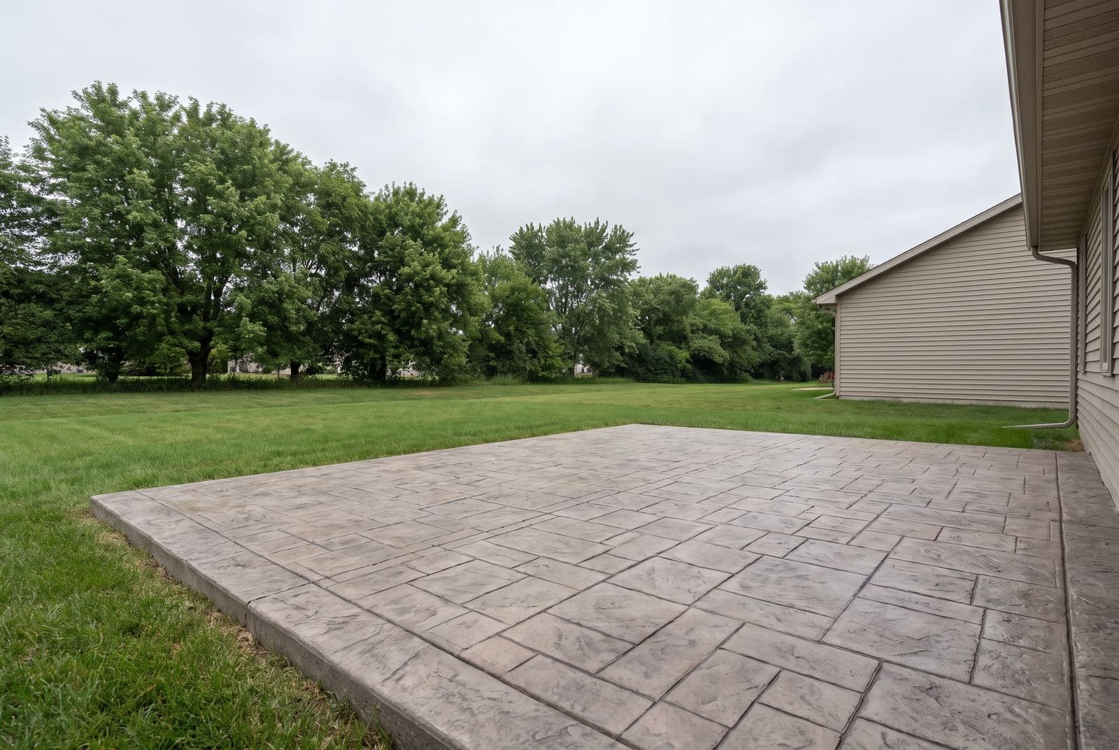 Stamped concrete patio with a slate-pattern finish beside a house